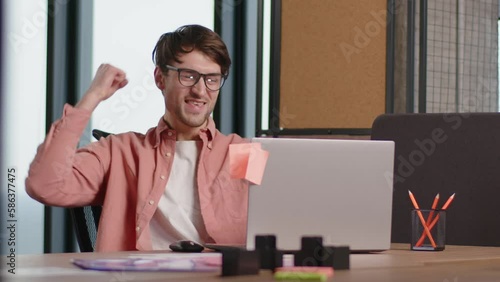 Excited young fan freelancer employee looking at laptop computer screen watch online sport game cheering man celebrating win goal rejoices victory good news at office workplace success great result