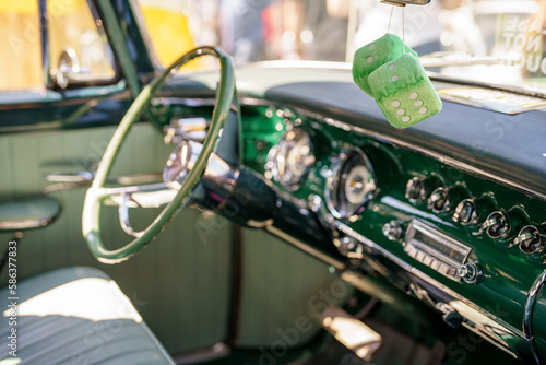 Fuzzy dice hanging from the mirror in a classic American car