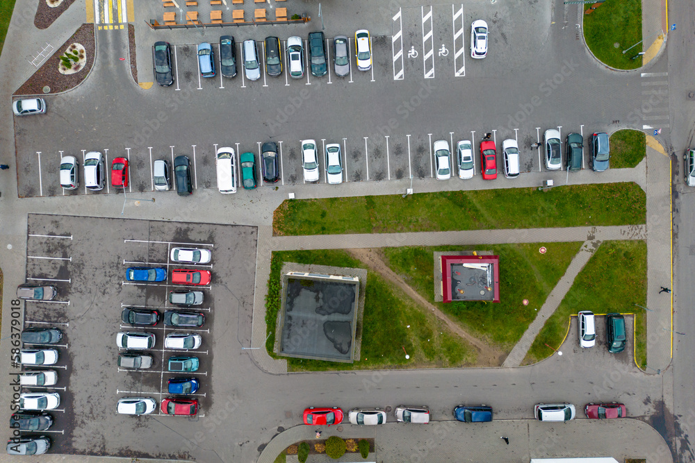 Aerial view of a large parking lot full of cars. Drone flying over the city and car parking. Large Parking lot near the shopping center.