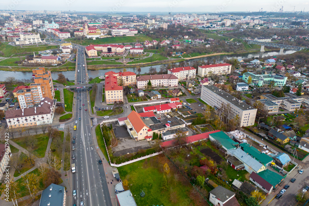 Obraz premium Top view of the historical center of the city. Flying a drone over the roofs of houses and a bridge over the river. The long main street of the city during the day.