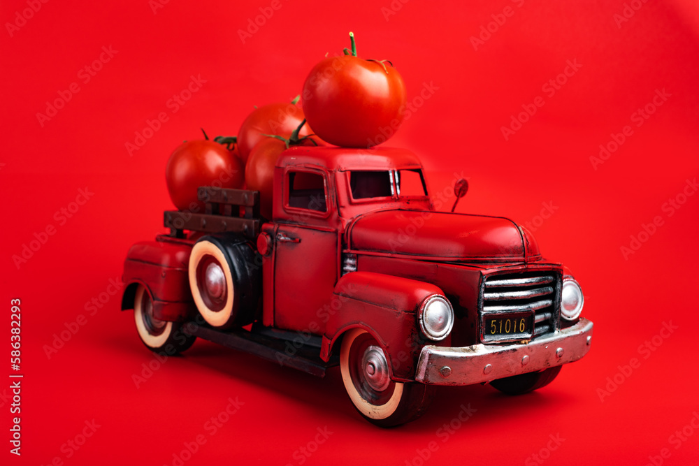 retro pickup truck carries fresh tomatoes on a red background, harvesting, and creative presentation of the product.