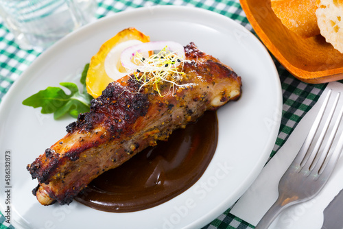 Image of tasty pork ribs baked under a mustard sauce, served with spicy sauce