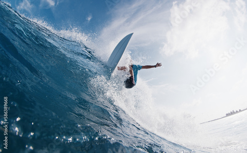 Pro surfer rides the wave. Young man surfs the ocean wave in the Maldives and aggressively turns on the lip. Splitted above and underwater view