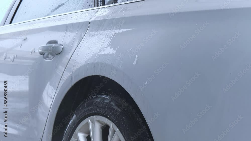 Washing luxury silver car on touchless car wash. Washing sedan car with foam self-service and high pressure water. Winter cleaning in car wash. Cleanliness and order in urban environment Washing luxury silver car on touchless car wash. Washing sedan car with foam self-service and high pressure water. Winter cleaning in car wash. Cleanliness and order in urban environment