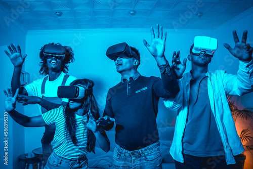 Group of young people in vr glasses in a virtual reality game in a blue light, amazed touching virtual objects, futuristic or science, technology concept
