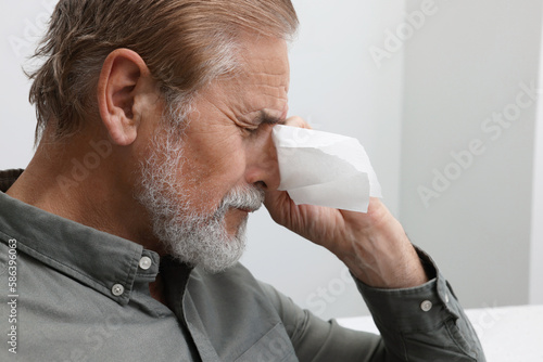Upset senior man wiping tears with napkin at home, closeup. Loneliness concept