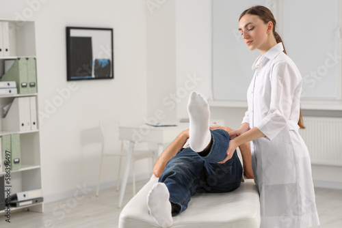 Professional orthopedist examining patient's leg in clinic