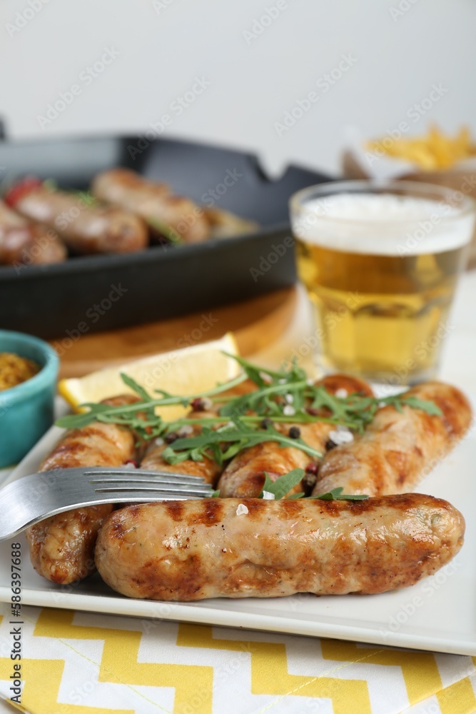 Tasty grilled sausages served with arugula and beer on table, closeup Tasty grilled sausages served with arugula and beer on table, closeup