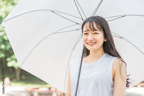 梅雨に傘を持ったアジア人女性(笑顔・カメラ目線) 