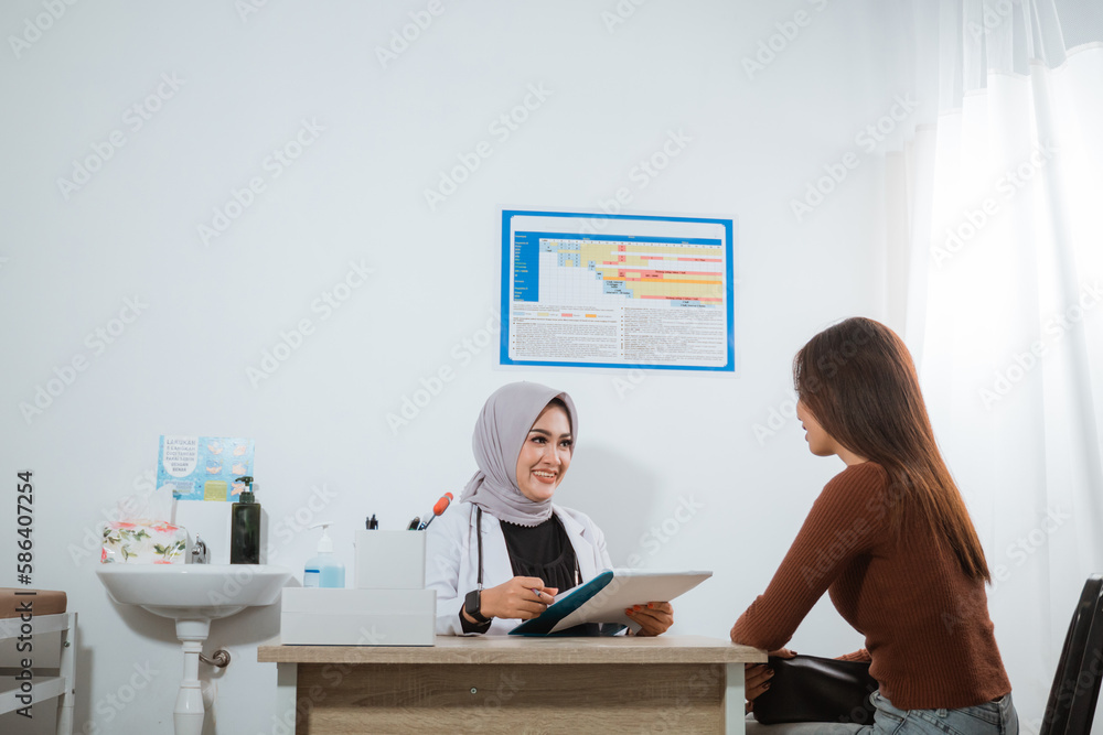 Obraz premium a female patient in brown clothes sitting next to the doctor's desk with the female doctor in doctor's coat