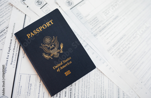 Close-up of a US passport with immigration, visa, citizenship, and travel paperwork on a wooden table photo