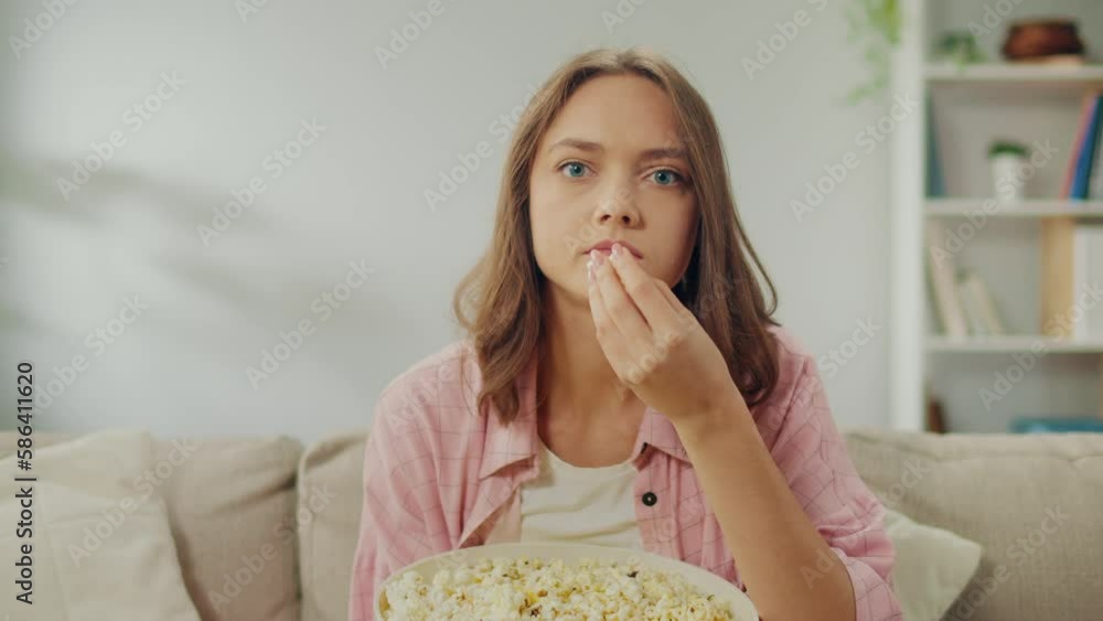 A Young Woman Eating Popcorn and Concentrating on Watching TV. A Serious Woman Sitting on the Sofa and Watching a Very Interesting Movie. Movie Genres and Emotional Response. Cinema and Its Role. A Young Woman Eating Popcorn and Concentrating on Watching TV. A Serious Woman Sitting on the Sofa and Watching a Very Interesting Movie. Movie Genres and Emotional Response. Cinema and Its Role.