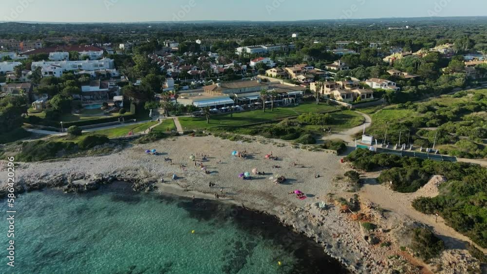Aerial drone view of small village town on the coastline with people lying on the sand.