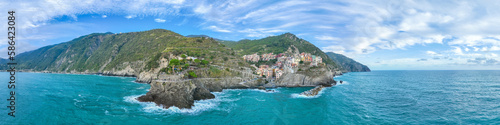 Aerial panorama top view of Manarola colorful fishing village one of five Cinque Terre national park, sequence of hill cities along the coastline of Ligurian Sea in Italy. Popular travel destination. #586423084