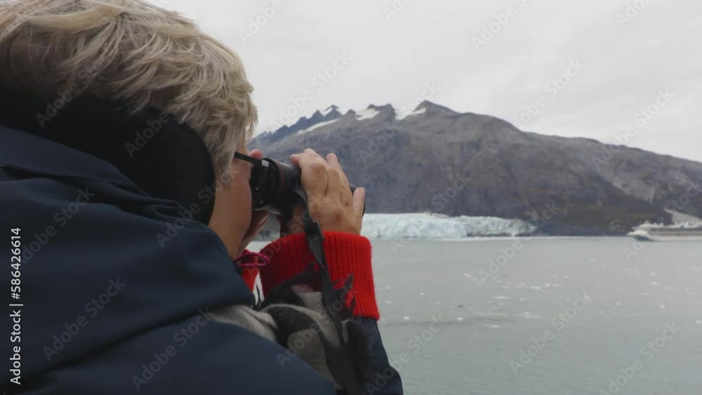Senior on Cruise ship in Alaska Glacier Bay. Tourist looking at Margerie Glacier with binoculars on cruise ship living active seniors lifestyle. People on vacation travel cruising famous destination Senior on Cruise ship in Alaska Glacier Bay. Tourist looking at Margerie Glacier with binoculars on cruise ship living active seniors lifestyle. People on vacation travel cruising famous destination