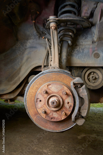 old and rusty car disk brake and caliper with steering knuckle and suspension without wheel, car care and safety concept, car maintenance in selective focus with copy space