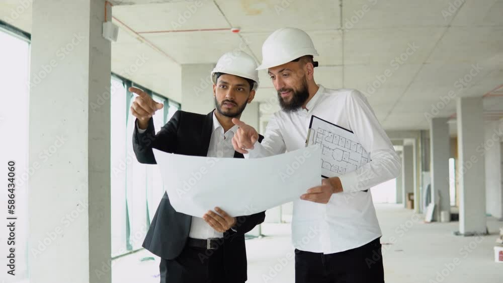 Indian architect and arabian supervisor meeting at construction site. Multiethnic engineers discussing on plan. Two construction workers working together while visiting a new building Indian architect and arabian supervisor meeting at construction site. Multiethnic engineers discussing on plan. Two construction workers working together while visiting a new building