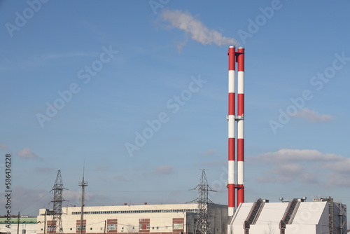 Exterior of a district heating station with industrial chimneys against a blue sky. Smoke coming out of the chimneys of industrial power plants.