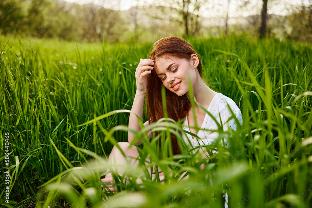 cute, contented woman sitting in tall green grass outdoors cute, contented woman sitting in tall green grass outdoors