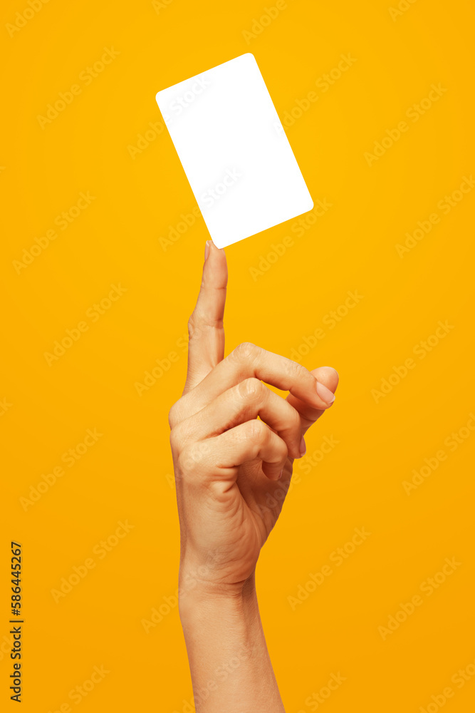 Woman's hand showing, or fingertip holding, or juggling business card or card or voucher, on orange yellow gradient color background Woman's hand showing, or fingertip holding, or juggling business card or card or voucher, on orange yellow gradient color background