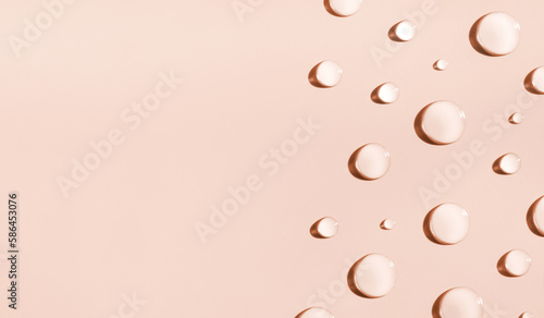 round drops of transparent gel serum on beige background with place for text