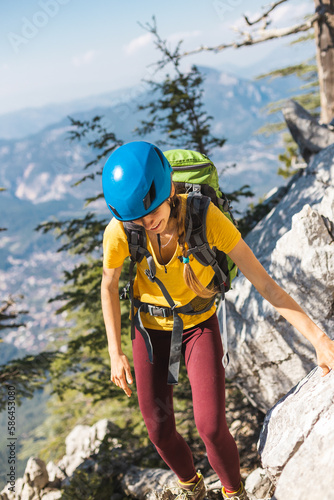 Woman climber with a backpack and a helmet in the mountains. A girl with a backpack walks along a mountain range. adventure and mountaineering concept. mountains of Turkey.