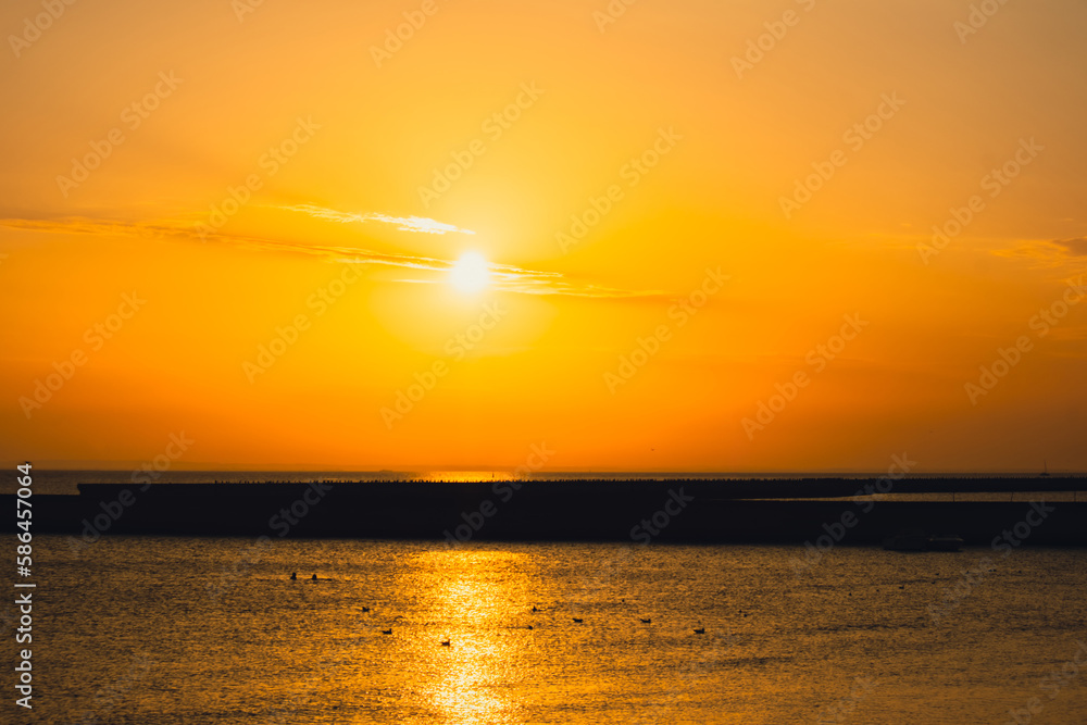Reflection of sunlight over sea surface at sunset. Orange and gold blue sky. Scenic Gold sea. Dramatic Yellow sun coming out of the sea. Majestic summer landscape