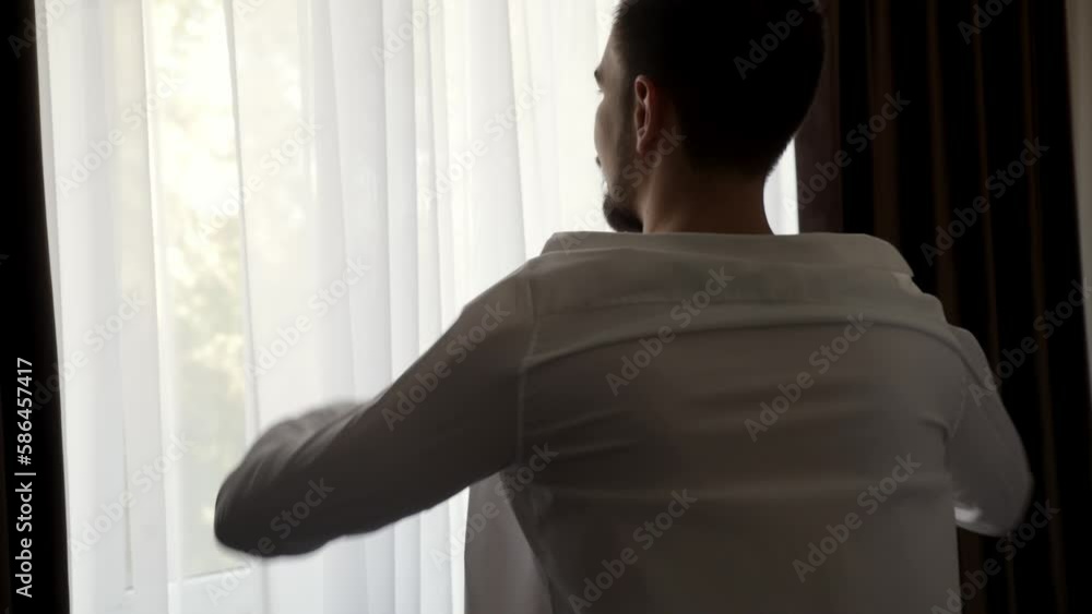 Close-up of a man puts on a shirt. Business man put on suit during morning routine at home getting ready for work Close-up of a man puts on a shirt. Business man put on suit during morning routine at home getting ready for work