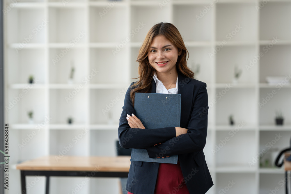 Confident young asian businesswoman embracing portfolio in recording plans, financial goals, online business and work wish list record of successful women. Confident young asian businesswoman embracing portfolio in recording plans, financial goals, online business and work wish list record of successful women.