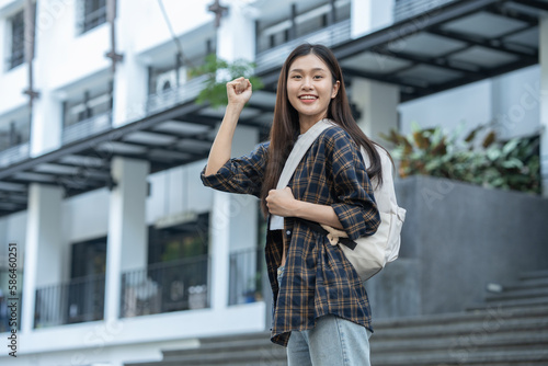 Young Asian female student standing with a beautiful smile carrying a backpack Confidence in preparation for submitting a biological report at university.