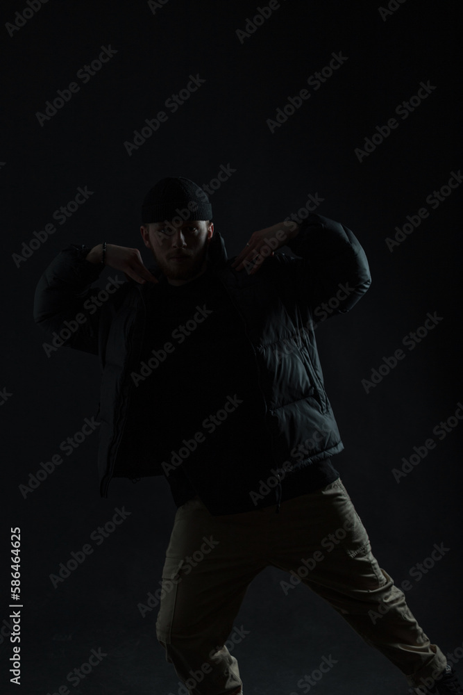 Fashionable professional dancer guy in stylish black clothes is dancing in the dark. Dancing man silhouette