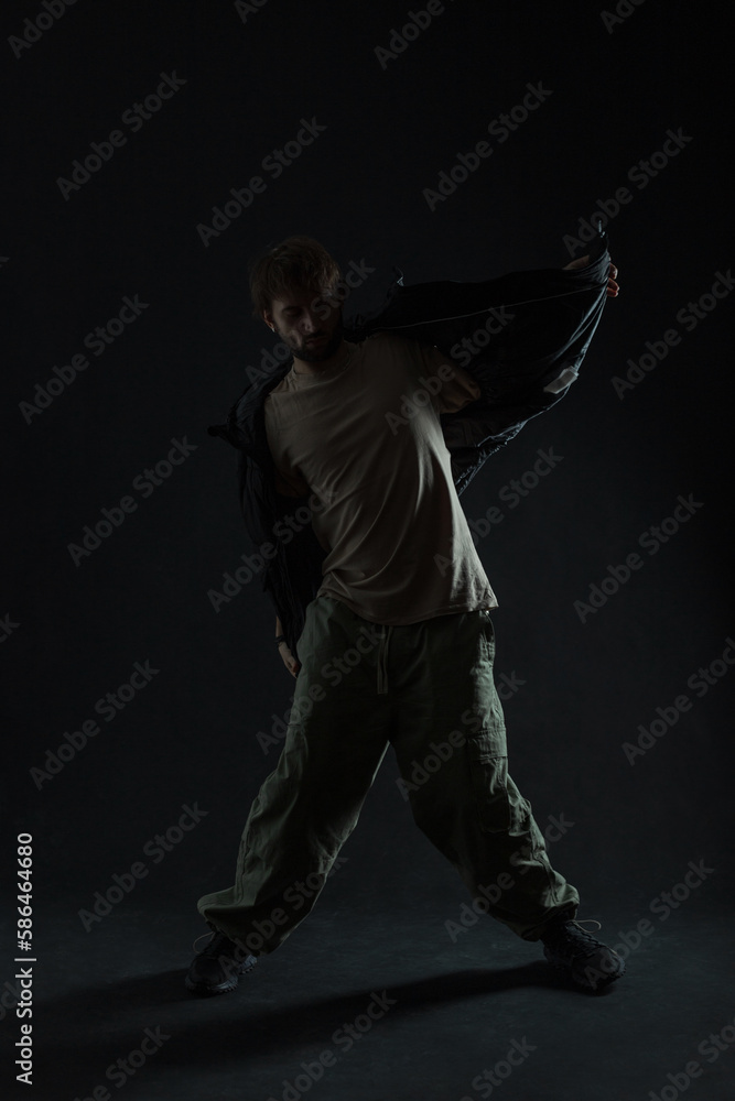 Fashion silhouette of a dancing stylish man in trendy clothes dancing in the dark