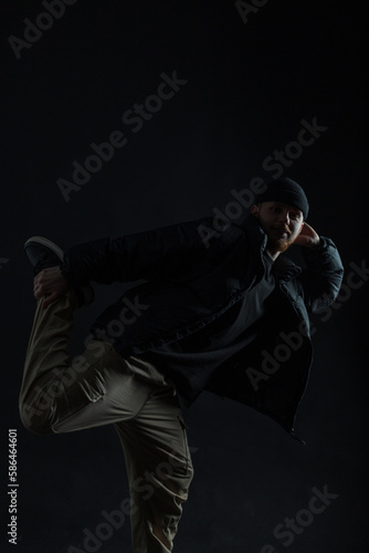 Stylish trendy man in fashion clothes dancing and posing in the dark