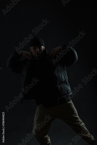 Fashionable professional dancer guy in stylish black clothes is dancing in the dark. Dancing man silhouette © alones