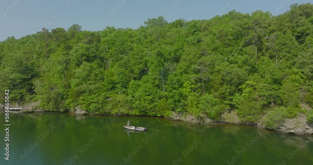 Aerial: Drone Panning Shot Of Man Fishing In Motorboat On River During Sunny Day - Tuscaloosa, Alabama Aerial: Drone Panning Shot Of Man Fishing In Motorboat On River During Sunny Day - Tuscaloosa, Alabama