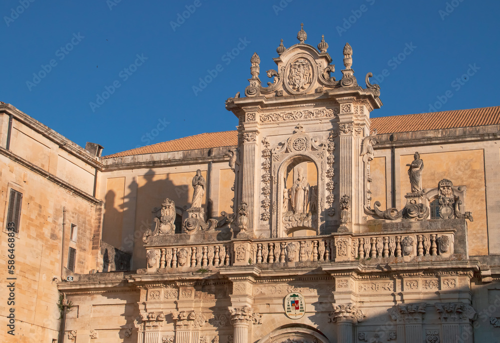 Fachada norte de la catedral de la Asunción de Santa María en Lecce, Italia. Detalles arquitectónicos barrocos del entablamento sobre el portal con la estatua de San Oroncio en el centro.