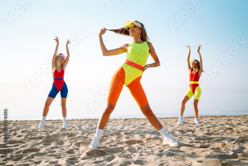 Three young woman - dancer dancing in bright swimsuits on the beach. Sport, fitness, active life.