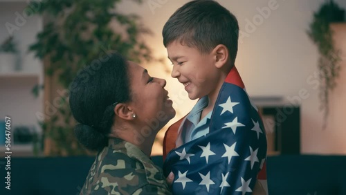 Biracial military mother and son wrapped in US flag nuzzling, patriotic family photo