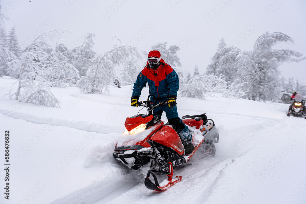 Athletes on a snowmobile moving in the winter forest in the mountains of the Southern Urals