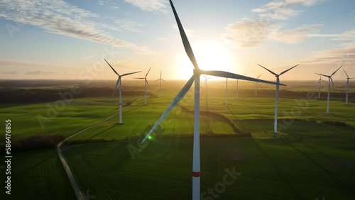 Aerial footage of wind farm by sunrise with wind turbine, which rotors by spin momentarily concealing the sun and causing a fascinating play of light and shade. Large spinning wind turbine.