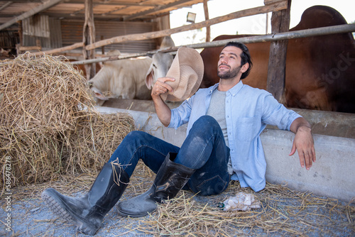 Portrait of successful farm worker rancher sitting in cow farm