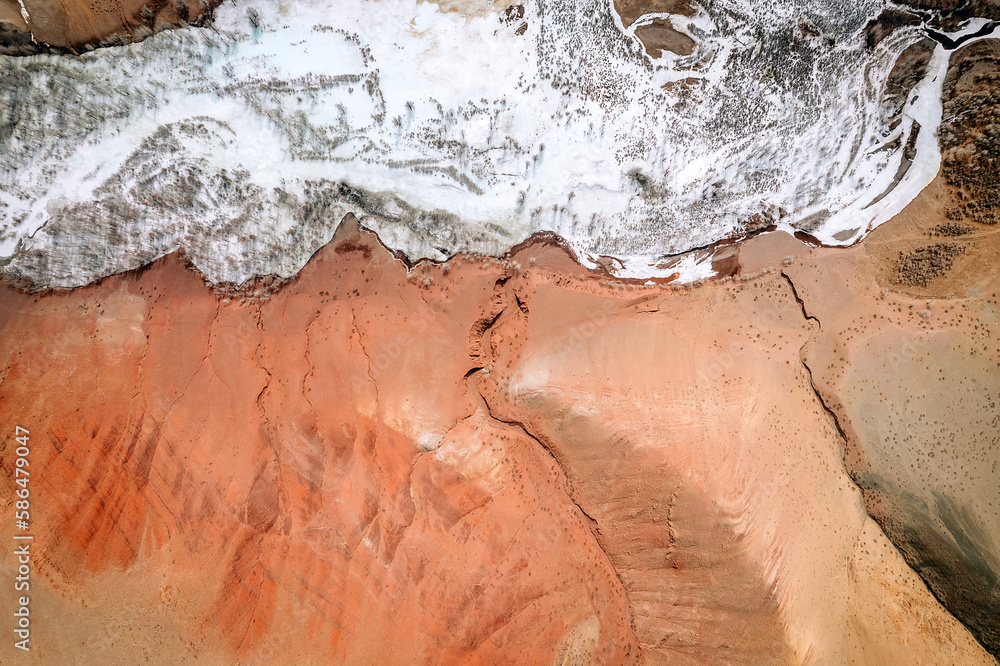 Photo taken from a high angle. A fragment of a huge red mountain and a nearby flowing clean reservoir.