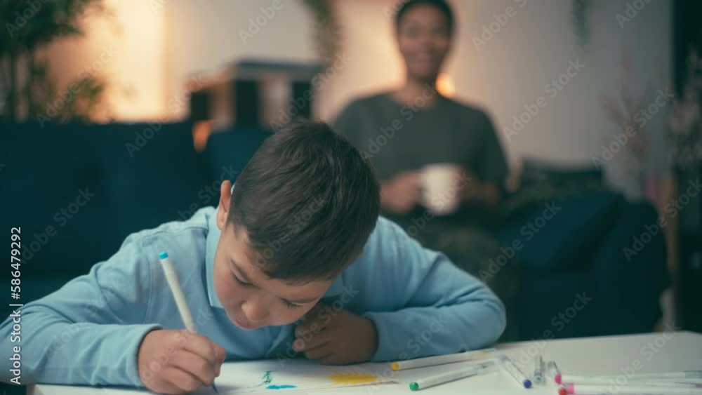 Loving mother admiring little son drawing picture and smiling, motherly care Loving mother admiring little son drawing picture and smiling, motherly care