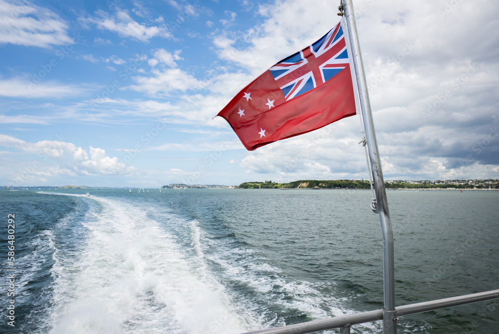 Fototapeta premium The New Zealand red ensign, also known as “the red duster” flies on the boat cruising Hauraki Gulf. New Zealand.