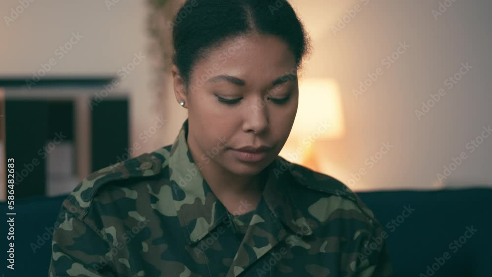 Upset military woman sitting in room, looking at framed photo, missing husband Upset military woman sitting in room, looking at framed photo, missing husband