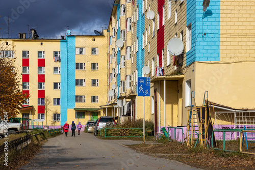 View of the street and colorful buildings in a small town. Children with school bags go home. Autumn season. Everyday life in provincial towns and villages in Russia. Klyopka  Magadan Region  Russia.