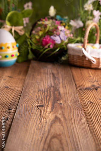 Easter theme. Easter decorations. Easter eggs in basket and easter bunny. Bouquet of spring flowers. Rustic wooden brown table.