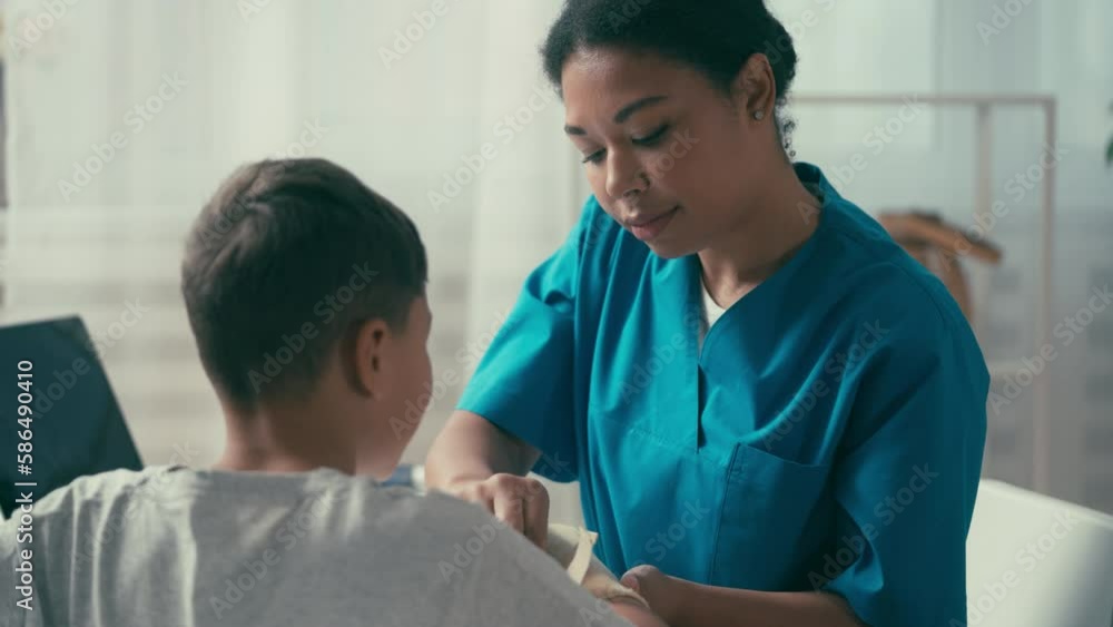 Traumatologist carefully examining boy with injured arm in clinic, treatment Traumatologist carefully examining boy with injured arm in clinic, treatment