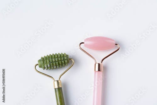 Fototapeta Naklejka Na Ścianę i Meble -  Two cosmetic facial rollers, rose quartz crystal and jade isolated on white background, top view