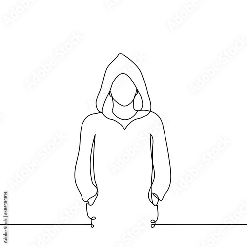 man with hoodie stands looking at the viewer, on his head is a hood with hands in pockets